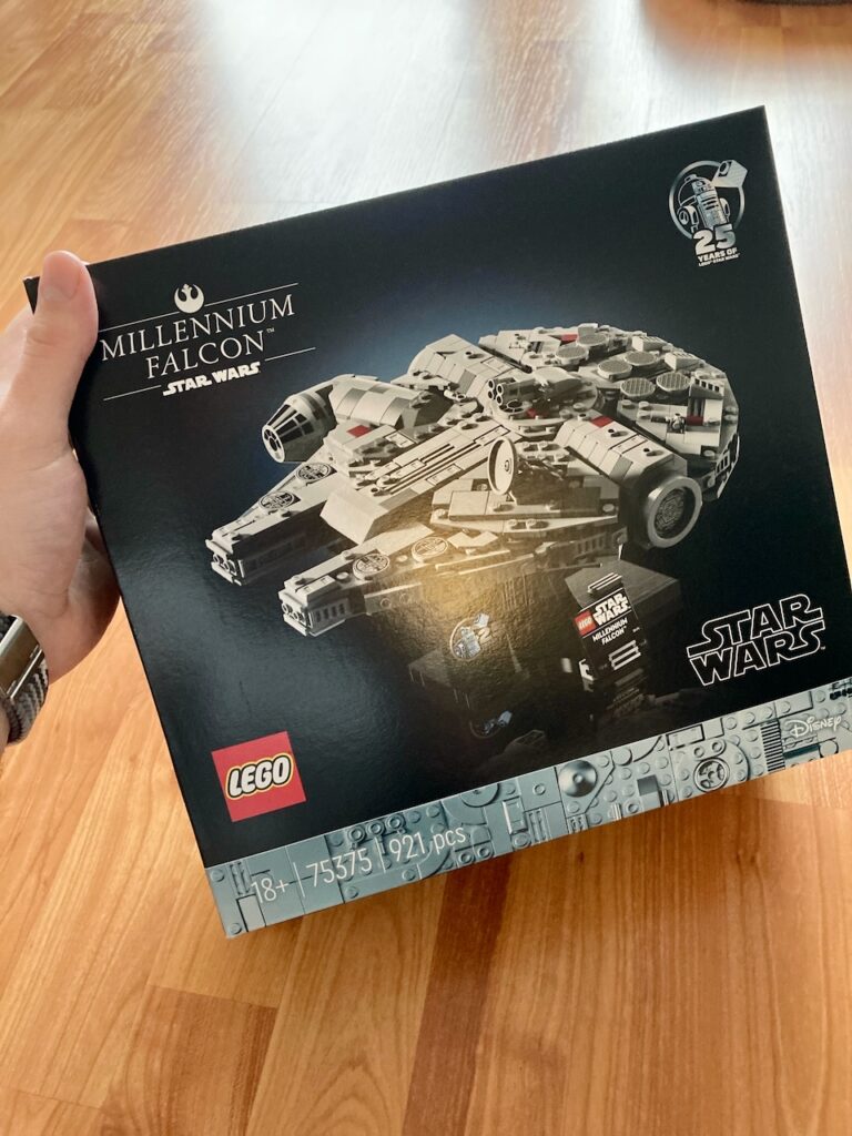 Eine geschlossene LEGO-Schachtel, die ein Modell des Millennium Falcon aus Star Wars darstellt. Die Verpackung ist dunkel mit Bildern und Text, die das fertige Modell und die Marke LEGO zeigen.